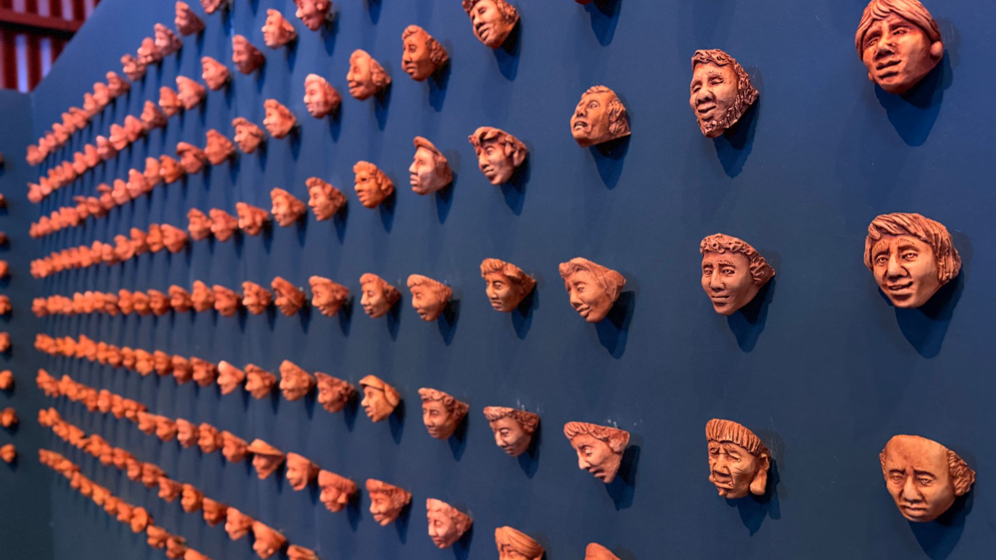 Criado pelo artista Bruno Souza, o painel de máscaras da Estrada de Ferro Madeira-Mamoré homenageia os trabalhadores que construíram a ferrovia. A obra foi produzida com o barro deixado pela enchente histórica do Rio Madeira, em 2014.